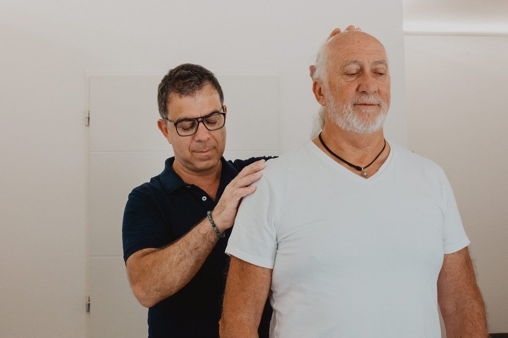 Philippe Kaladjian examine l'épaule d'un patient adulte debout