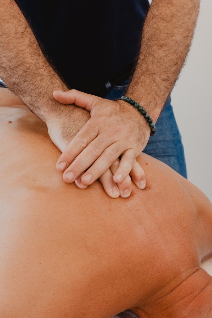 Gros plan sur les mains de l'ostéopathe posées sur le dos d'un patient