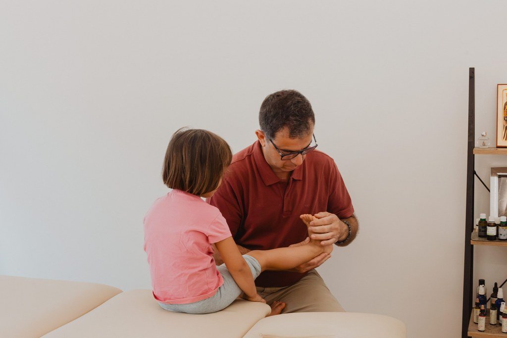 Séance d'ostéopathie pédiatrique : une enfant assise sur la table de soin