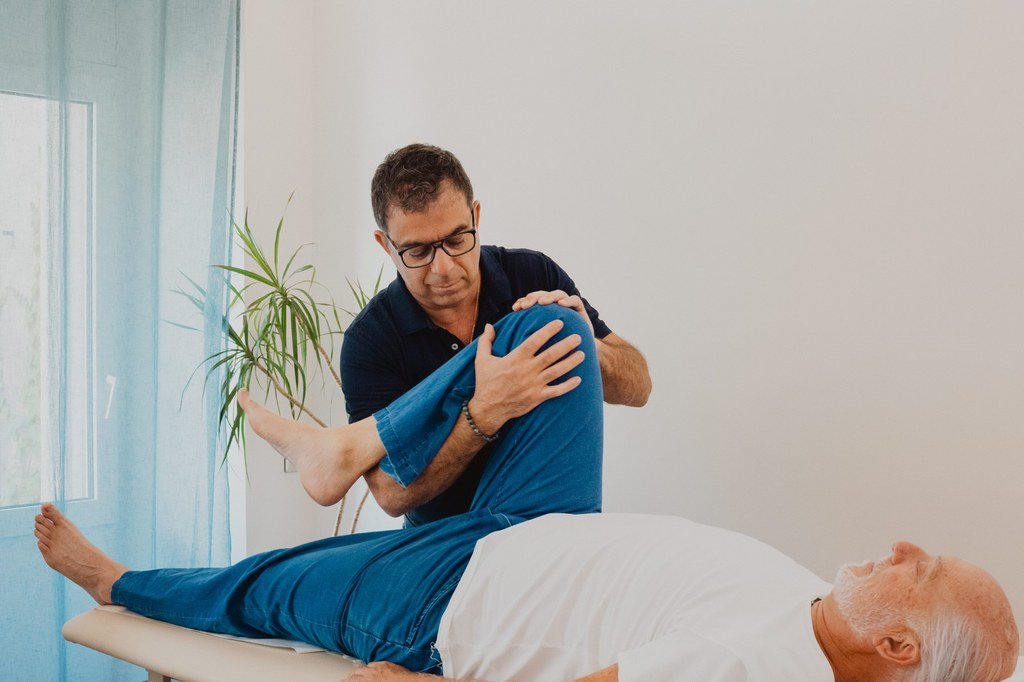 Mobilisation du genou d'un patient allongé sur la table de soin
